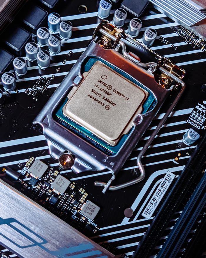 contact-img Detailed view of an Intel i7 processor installed on a computer motherboard.
